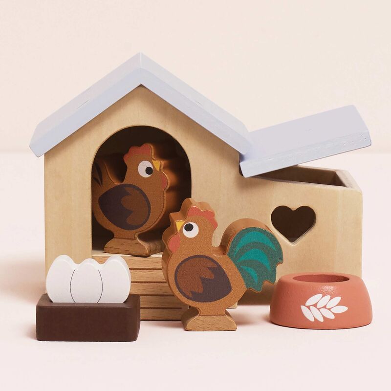 Wooden toy set with chickens and a coop on a beige background