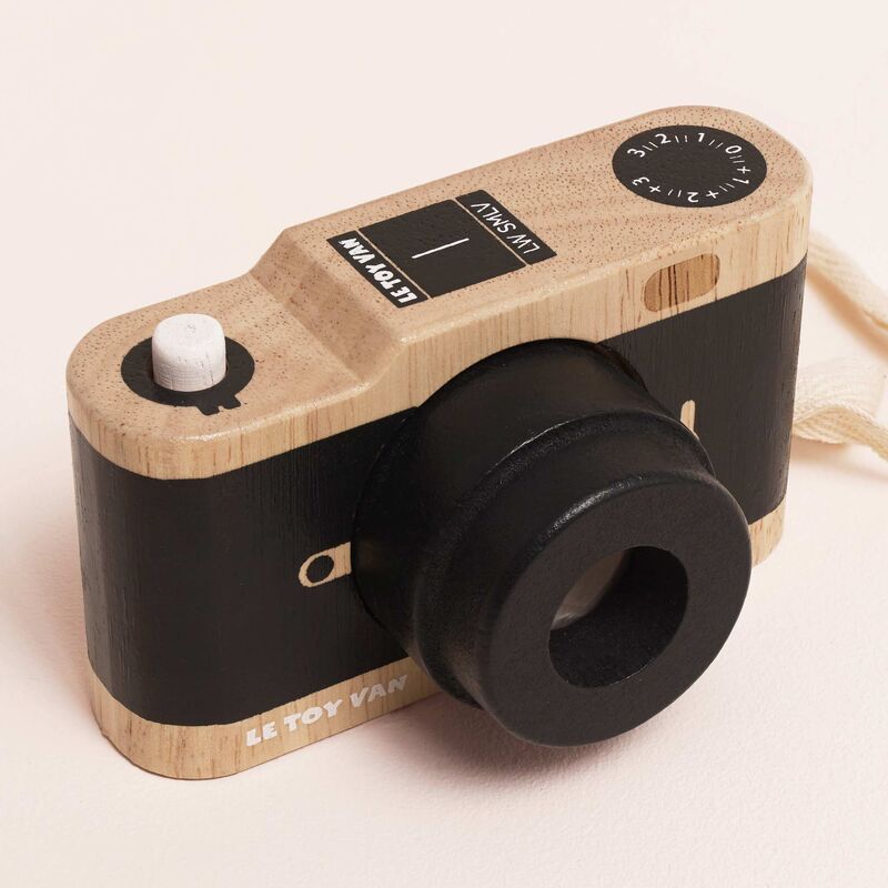 Wooden toy camera with black accents on a light pink background