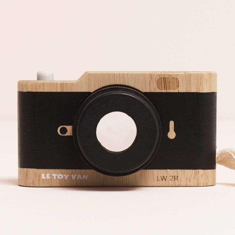 Wooden toy camera with black lens and 'Le Toy Van' branding on a beige background