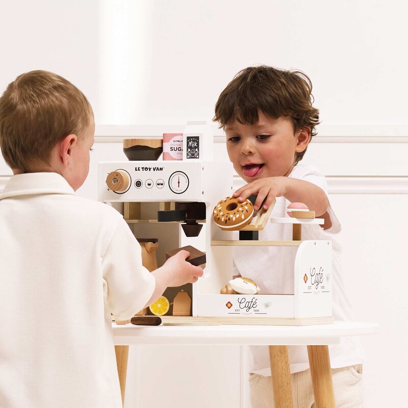 Two children playing with tabletop cafe set on a white background