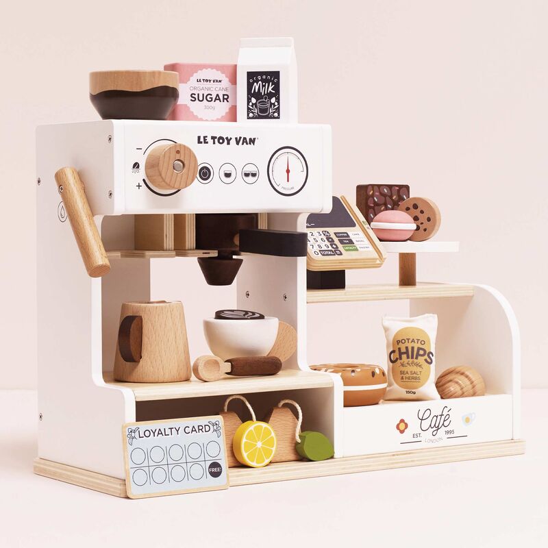 Wooden toy café set with various items on a light pink background