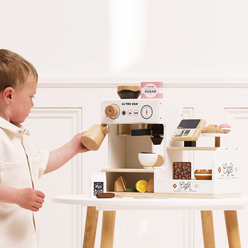 Child playing with a toy coffee set in a home setting