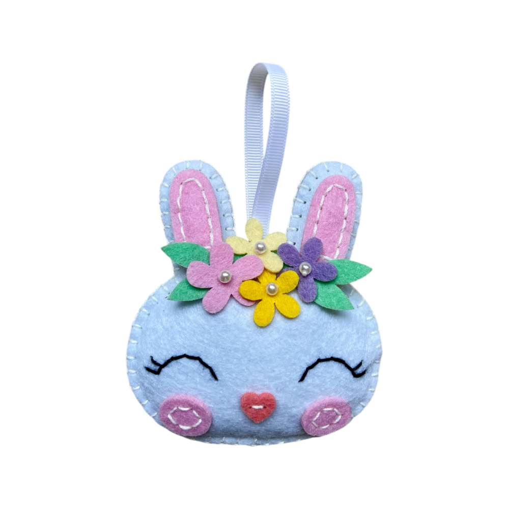 Blue felt bunny ornament with flowers and a ribbon on a white background