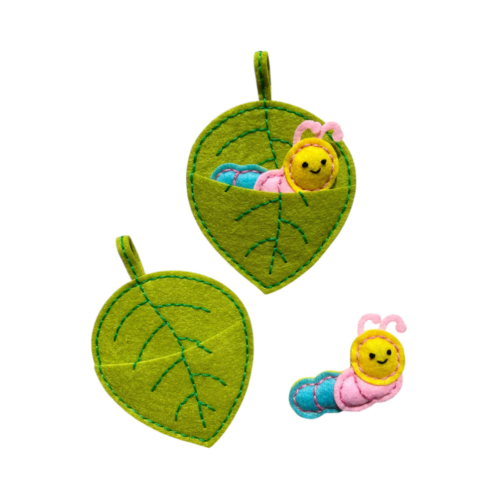 Felt caterpillar and leaves on a white background