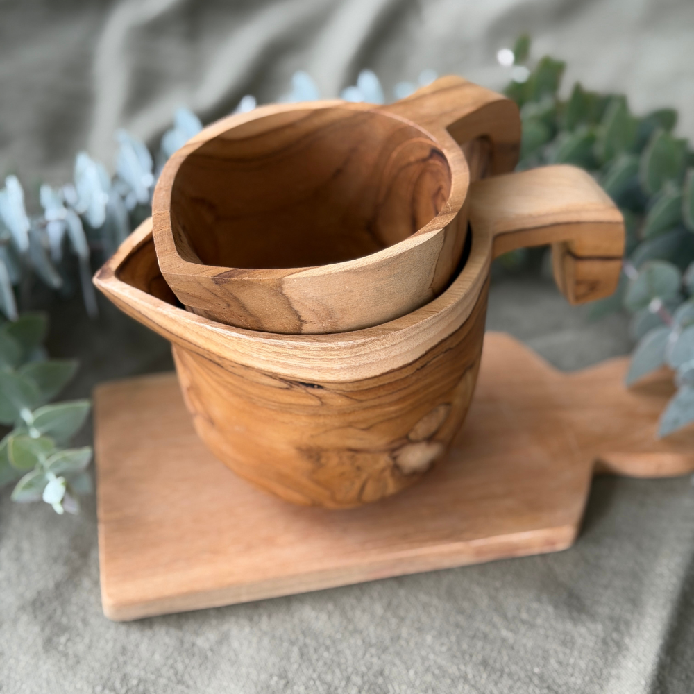 Wooden mug and bowl set on a wooden coaster with plants in the background
