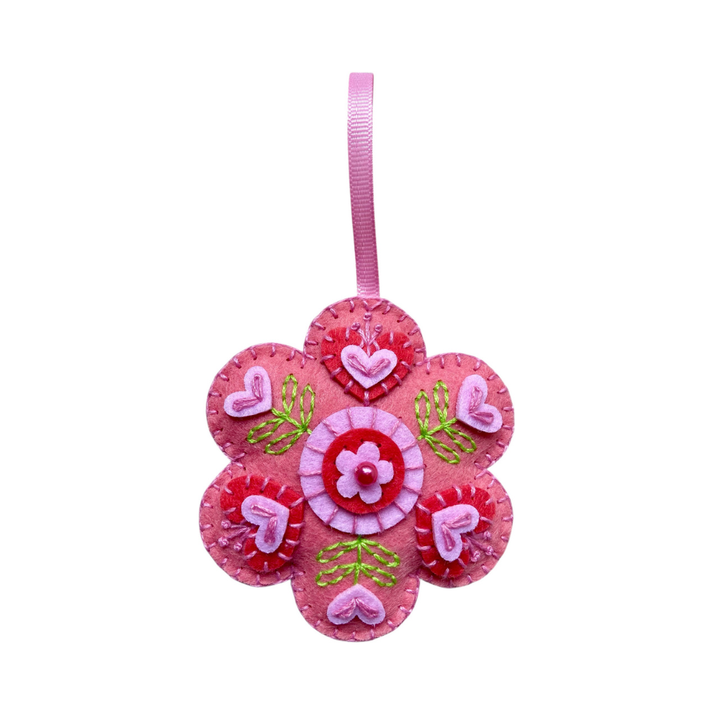 Pink flower-shaped decorative item with hearts and ribbons on a white background