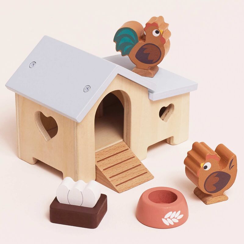 Wooden toy chicken coop with chickens on a light pink background